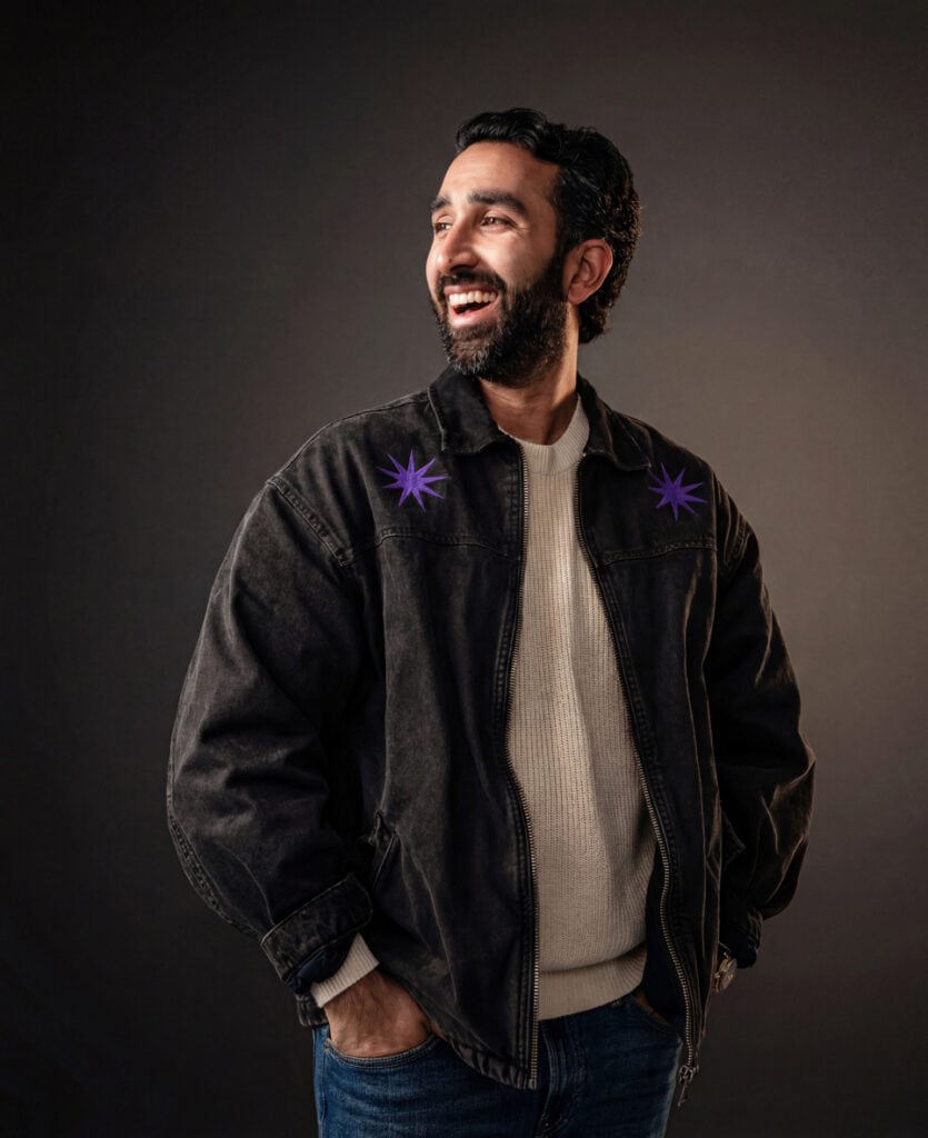 Manick Bhan smiling in casual outfit for brand identity.